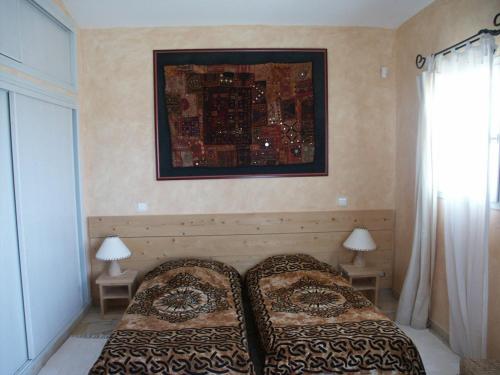 une chambre avec deux lits et un tableau au mur dans l'établissement BLU DI MARE Palombaggia, à Porto-Vecchio