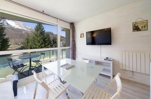 a white table and chairs in a room with a large window at A la montagne in Eaux-Bonnes