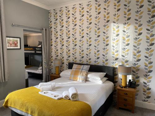 a bedroom with a bed with towels on it at The Wildings Hotel & Tudno's Restaurant in Llandudno