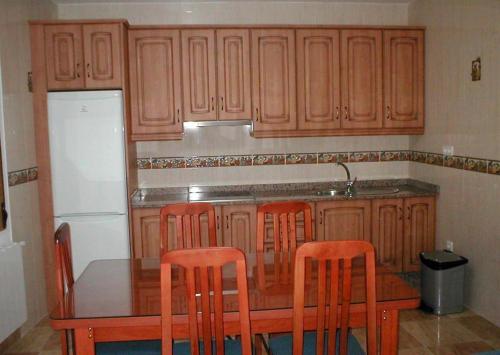a kitchen with wooden cabinets and a table with four chairs at Apartamentos Egeivan in Pontón Alto