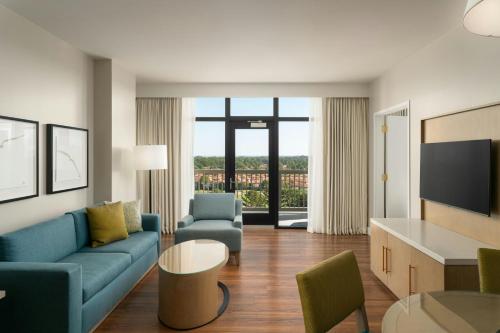 a living room with a blue couch and a tv at Hotel Effie Sandestin Resort, Autograph Collection in Destin