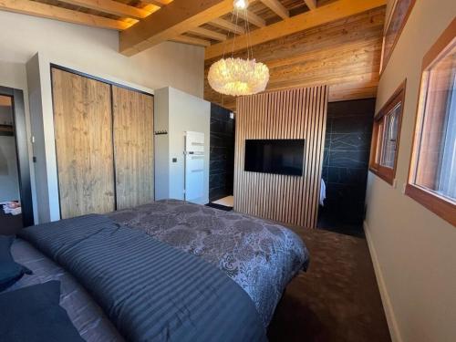 une chambre avec un grand lit et une télévision dans l'établissement Somptueux chalet, à Megève