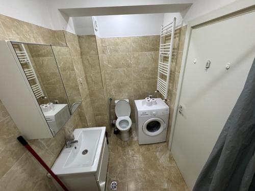 a bathroom with a toilet sink and a washing machine at Relax Apartment Militari Residence Sector 6 in Roşu