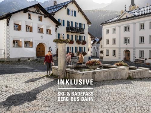 a group of people standing in a courtyard with buildings at Badehotel Belvair in Scuol