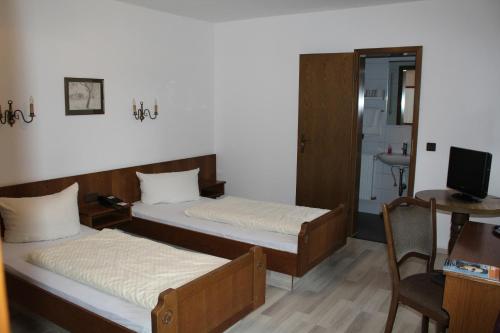 a bedroom with two beds and a desk and a television at Landhotel Sickinger Hof in Walldorf