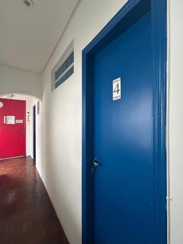 a blue door with a sign on it in a hallway at Pousada e Hostel São Paulo Comfort - Bairro Pinheiros, próximo Hospital das Clínicas e Incor, Oscar Freire, Av Paulista, Allianz, Vila Madalena e fácil acesso ao Ibirapuera e Morumbi in Sao Paulo