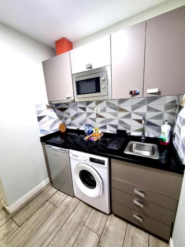 a kitchen with a sink and a washing machine at Hotel Apartamento Bajamar in Las Palmas de Gran Canaria