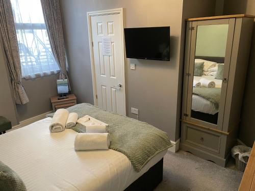 a bedroom with a bed with towels and a mirror at The Wildings Hotel & Tudno's Restaurant in Llandudno