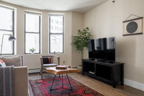a living room with a flat screen tv on a table at Classic Downtown Loft Style Apartment in Boston