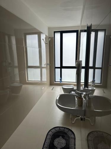 a bathroom with a sink and two toilets and a shower at SISI Apartment in Tirana