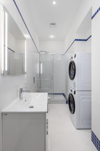 a white bathroom with a washing machine and a sink at K1820 Family apartments in Rīga