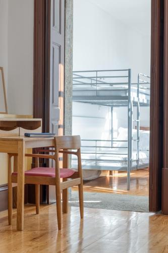 a table and a chair in a room with a bunk bed at Alado Guesthouse in Braga