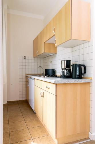 a kitchen with wooden cabinets and a counter top at FerienResidenz MüritzPark in Röbel