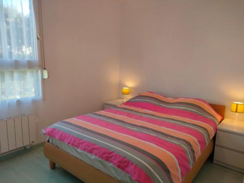 - une chambre avec un lit et une couverture rayée colorée dans l'établissement Ref 137 Appartement pour 2 vue port du Crouesty ARZON, à Arzon