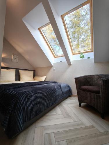 a bedroom with a bed and a chair and two windows at Apartament Górski Widok in Szklarska Poręba