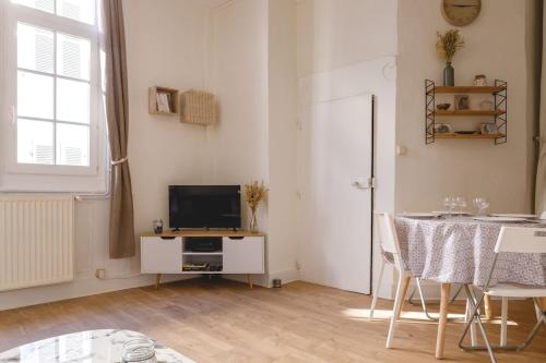 Il comprend un salon doté d'une télévision et d'une table avec des chaises. dans l'établissement L'Appart du Palais - Hypercentre au calme, à Bourg-en-Bresse