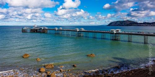 a pier in the ocean with rocks in the water at Downtown Cottage Conwy in Conwy