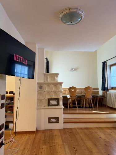 a television in a living room with a table and chairs at Cèsa Emily in Campitello di Fassa