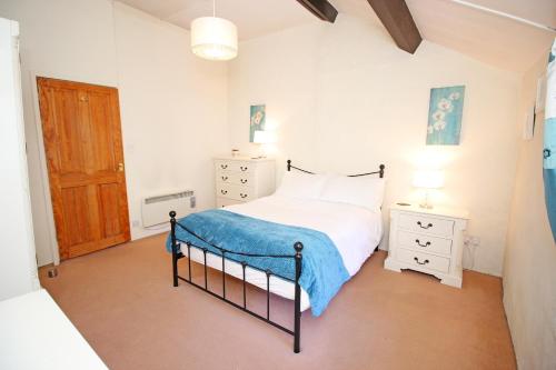 ein Schlafzimmer mit einem Bett mit einer blauen Decke darauf in der Unterkunft Hafan Cottage in Caernarfon