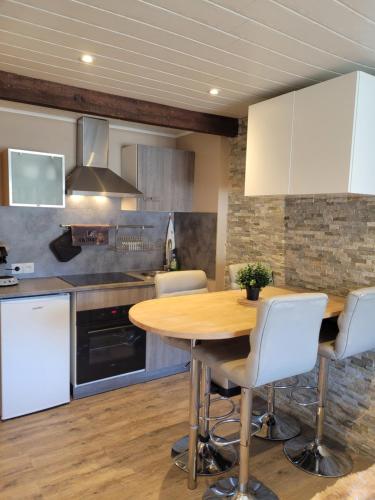 - une cuisine avec une table en bois et des chaises blanches dans l'établissement Studio cabine face au Cambre d'aze, à Saint-Pierre-dels-Forcats