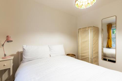 a bedroom with a white bed and a mirror at Cosy 1-Bed Flat by Central London in London