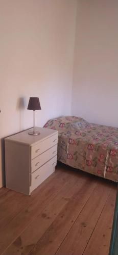 a bedroom with a bed and a dresser with a lamp at House with garden in Marinha da Mendiga in Casais do Chão da Mendiga
