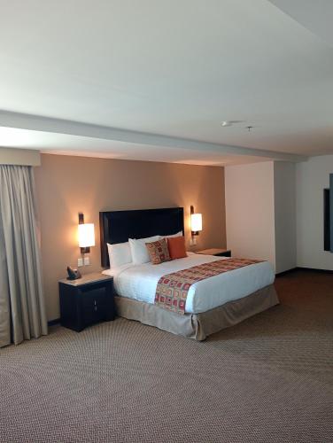 a hotel room with a large bed and two lamps at Ankara Pedregal Centro de Convenciones in San Luis Potosí