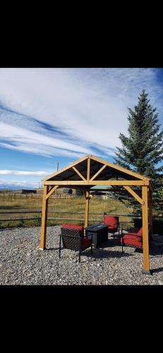a wooden pavilion with three benches and a table at Quiet Country Cabin in Waiparous Village