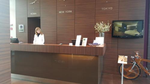 a woman standing at a reception desk in a lobby at Best Western Plus Hotel Monza e Brianza Palace in Cinisello Balsamo