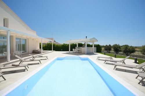 a swimming pool with chaise lounge chairs and a house at Villa Aria - Modica in Modica