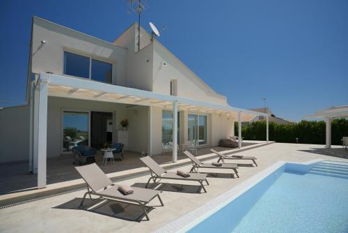 a villa with a swimming pool and chairs next to a house at Villa Aria - Modica in Modica