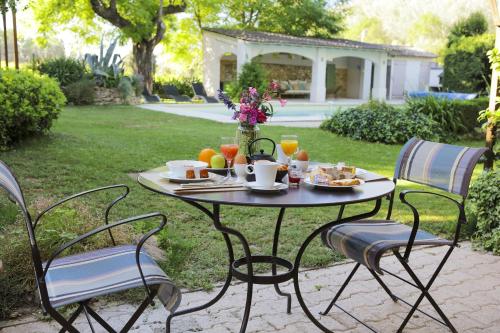 een tafel met eten en drinken erop in een tuin bij Logis Hôtel La Sommellerie in Châteauneuf-du-Pape