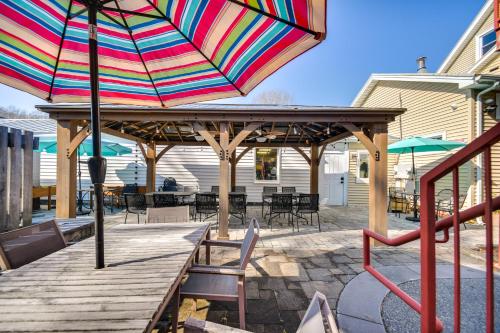 a colorful umbrella on a deck with tables and chairs at Family-Friendly Main St Gloucester Apt with Balcony! in Gloucester
