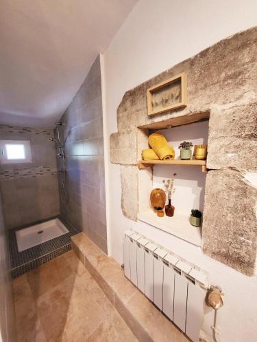 La salle de bains est pourvue d'une douche et d'un mur en pierre. dans l'établissement Le petit Mazet, à Ménerbes
