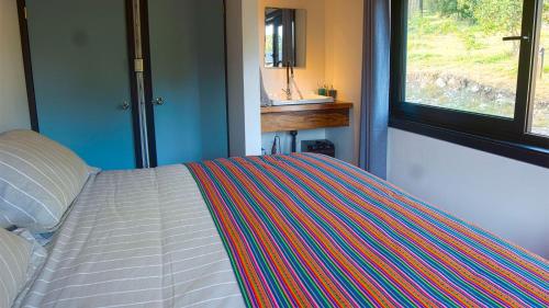 a bedroom with a bed with a striped blanket on it at K10 Lodge in Curacautín