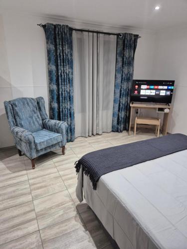 a bedroom with a bed and a chair and a television at Wattlewood Cabins in Piet Retief