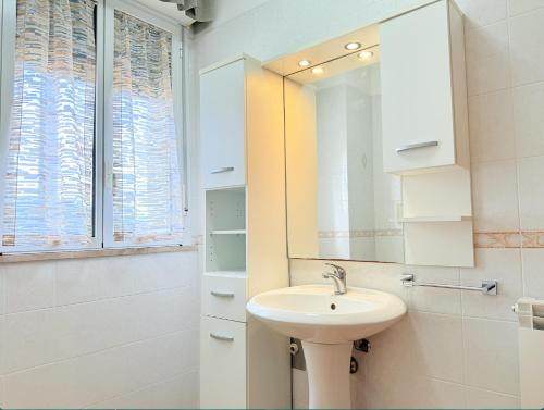 een witte badkamer met een wastafel en een spiegel bij Appartamento Spiga in San Vincenzo