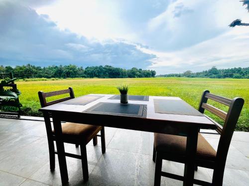 a table and chairs with a view of a field at Honey Dew Villa Minuwangoda in Balabowa