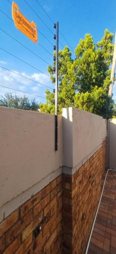 a street sign on top of a brick wall at Gugulethu Villa in Rensburgdorp
