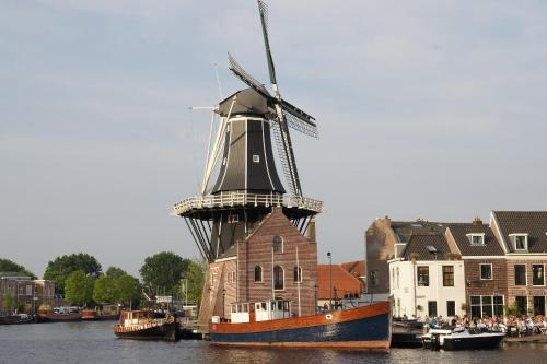 a boat with a windmill in the water at Villa Abbekerk - Bed & Breakfast in Abbekerk