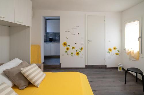 a bedroom with a yellow bed and flowers on the wall at Girasole in Chioggia