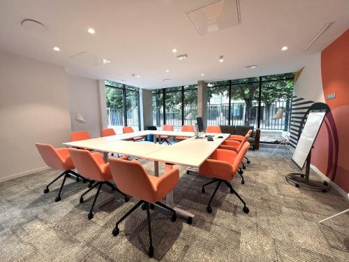 an office meeting room with a long table and orange chairs at Holiday Inn Express Paris - Poissy by IHG in Poissy