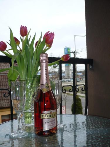 a bottle of wine sitting on a table with flowers at Adrienn Apartman in Sárvár
