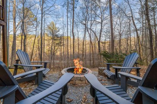 three chairs sitting around a fire pit in the woods at Creeksong in Ellijay