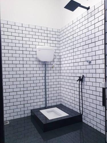 a white tiled shower with a toilet in a bathroom at Cikteh Homestay Besut in Kampung Raja