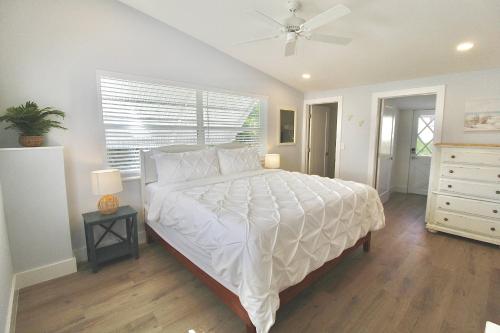 a bedroom with a white bed with a ceiling fan at Jensen Surf Shack in Jensen Beach