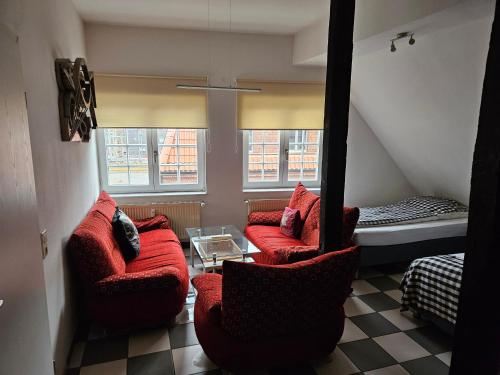 a living room with two red chairs and a bed at Haus mit 4 Ferienwohnungen am Fuselpättken in Sendenhorst