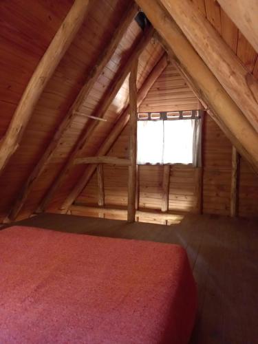 ein Schlafzimmer in einem Blockhaus mit einem Fenster in der Unterkunft Cabaña Alpina in Rodeo