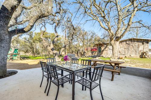 a glass table with chairs and a table with flowers on it at Pin Oak Farmhouse with Patio in Dripping Springs in Dripping Springs