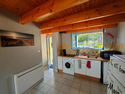 une cuisine avec un évier et une machine à laver dans l'établissement Maison cosy à 700 m de l'océan, à Bretignolles-sur-Mer